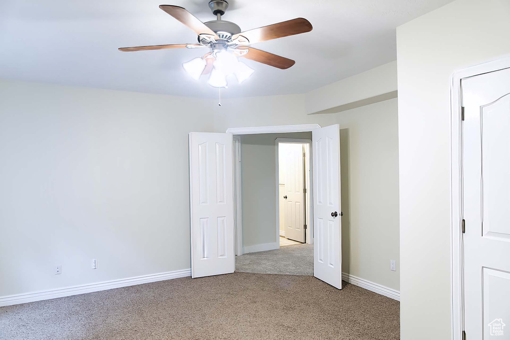Unfurnished bedroom with light colored carpet and a ceiling fan