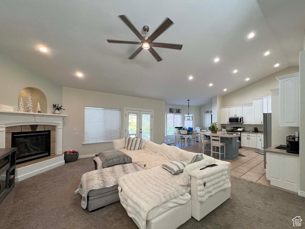 Living area with a ceiling fan, recessed lighting, light colored carpet, vaulted ceiling, and a fireplace