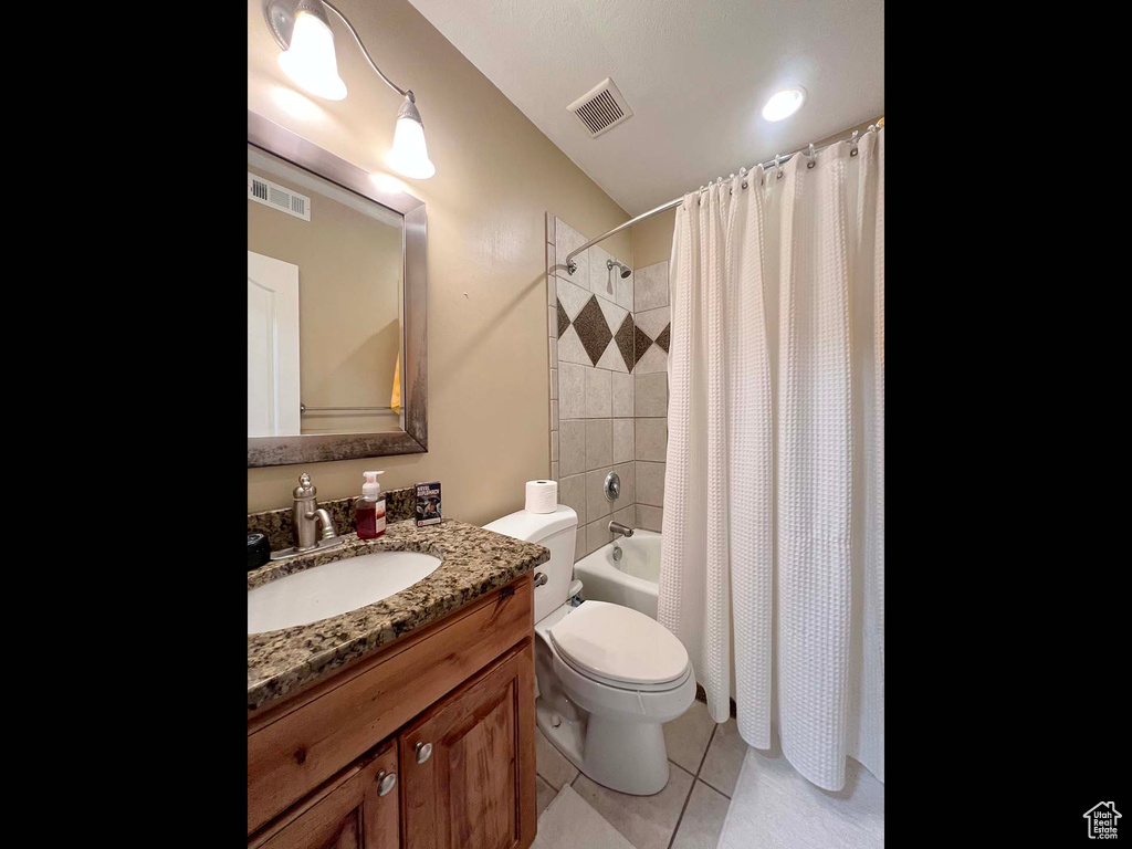 Bathroom featuring vanity, shower / bath combo, and tile patterned flooring