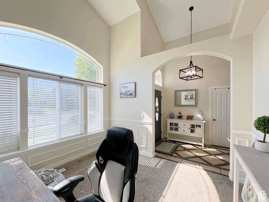 Home office with a chandelier, arched walkways, high vaulted ceiling, wainscoting, and inlaid floor details