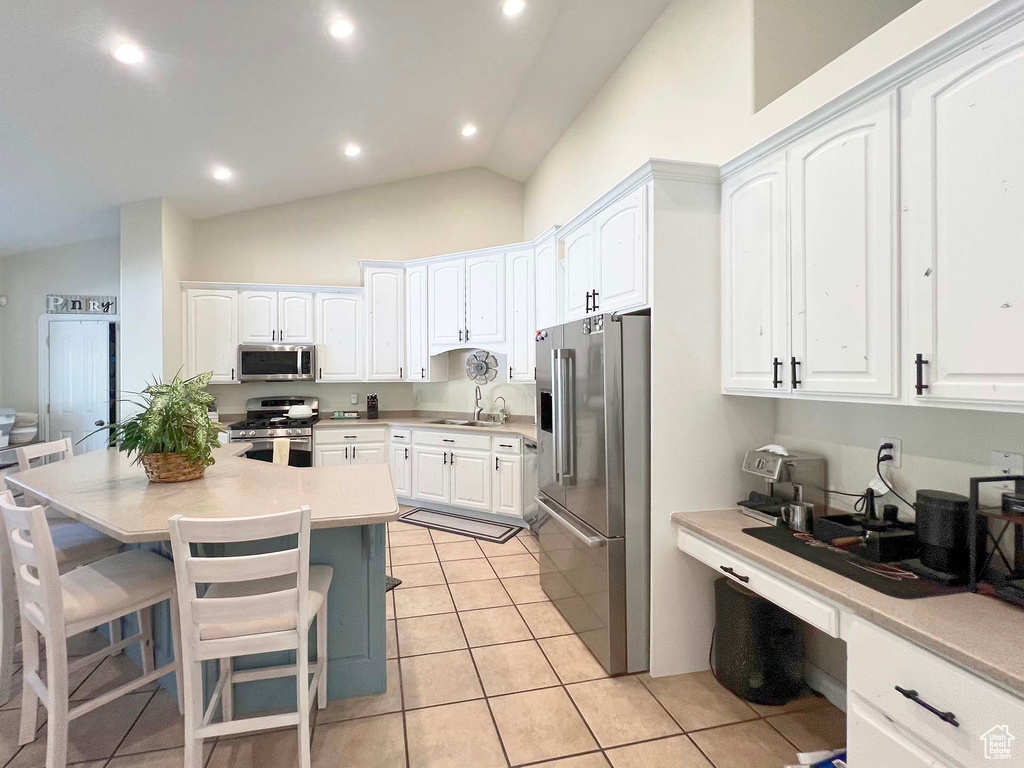Kitchen featuring appliances with stainless steel finishes, white cabinets, recessed lighting, and high vaulted ceiling