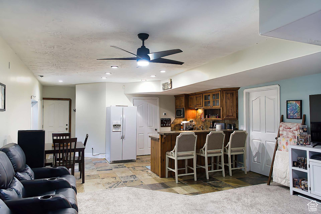Living room featuring a ceiling fan, recessed lighting, and light stone finish flooring