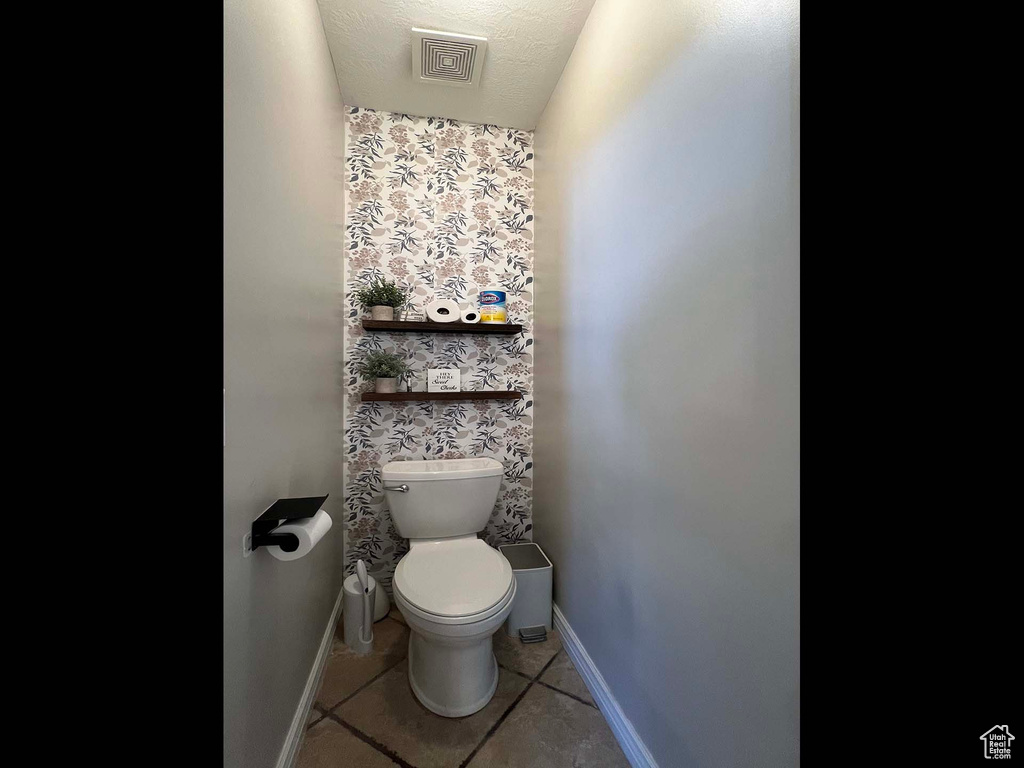 Bathroom featuring tile patterned flooring and wallpapered walls