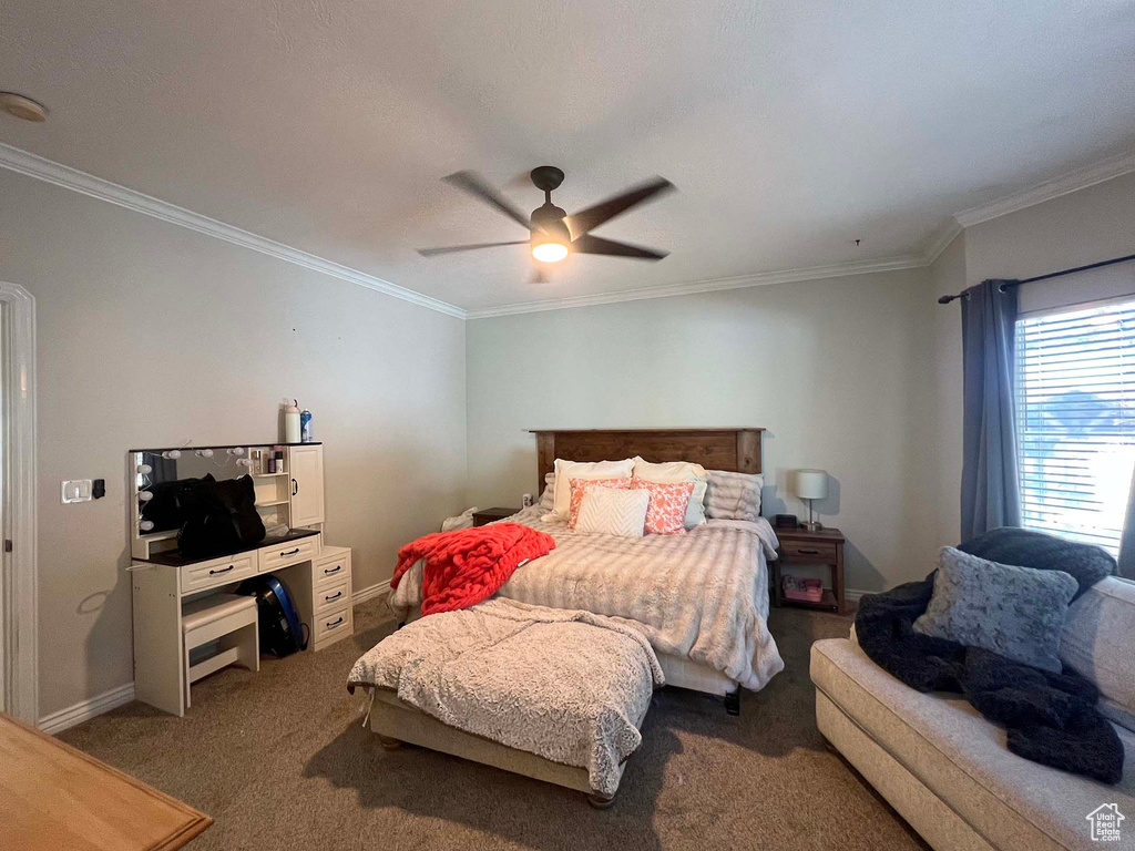 Carpeted bedroom with ornamental molding and a ceiling fan