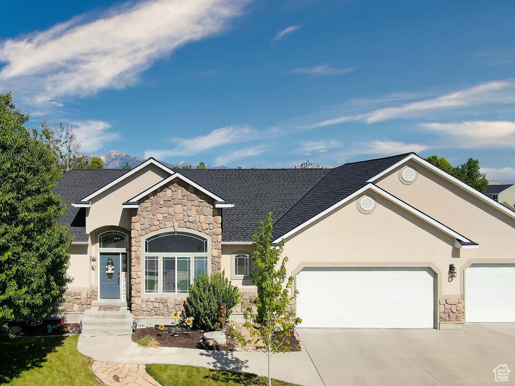 View of front of house featuring stone siding, stucco siding, and a garage