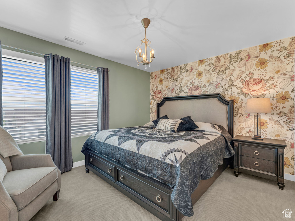 Bedroom with carpet floors, wallpapered walls, and a chandelier