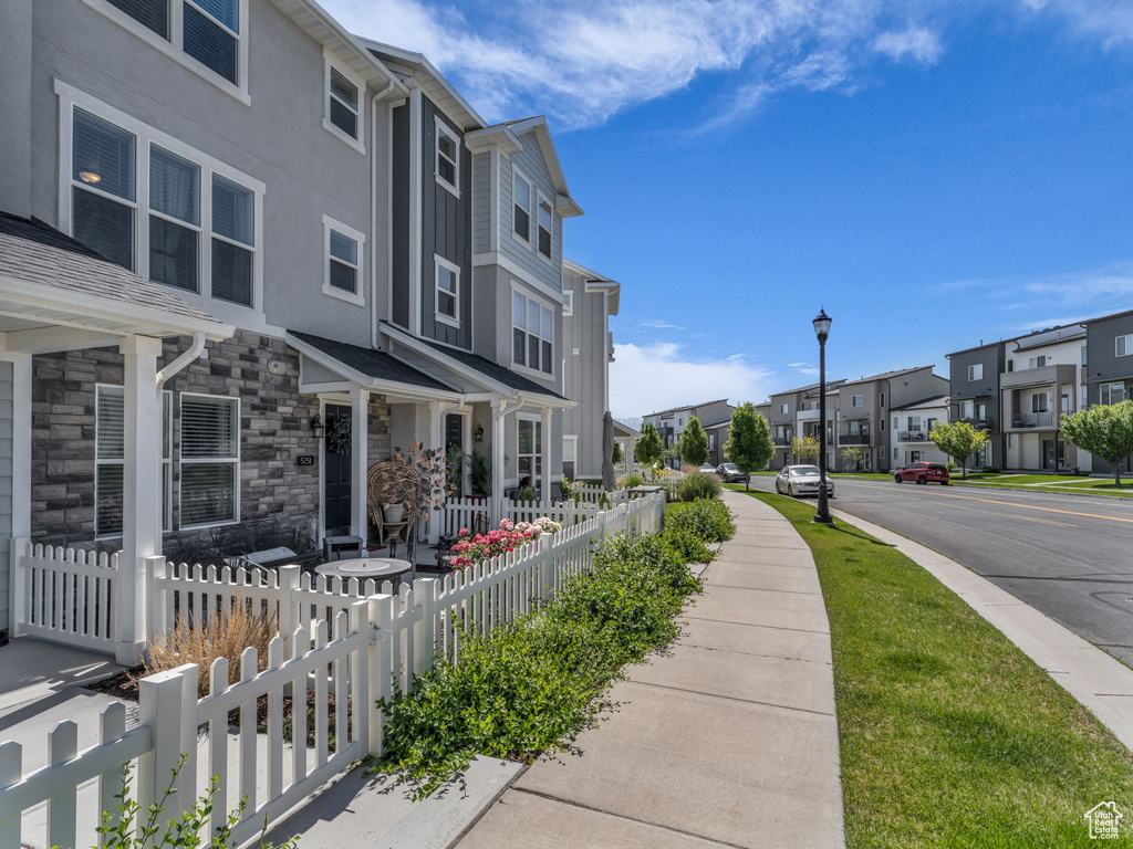 View of asphalt road featuring a residential view, sidewalks, street lighting, and curbs