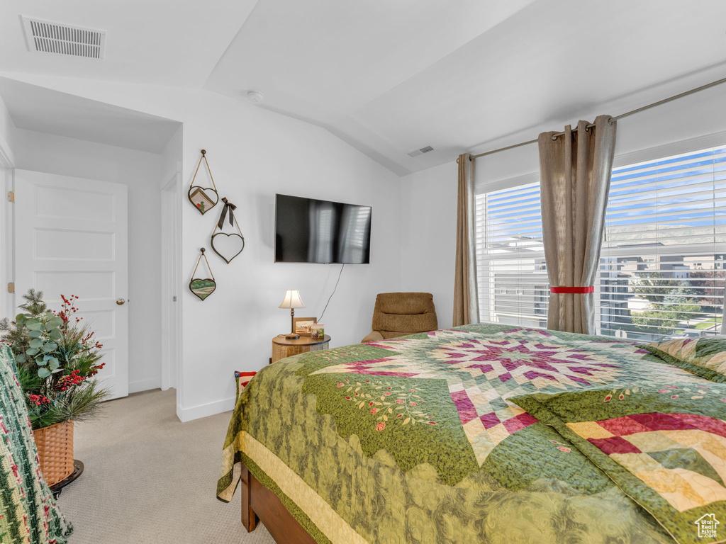 Bedroom featuring lofted ceiling and light carpet