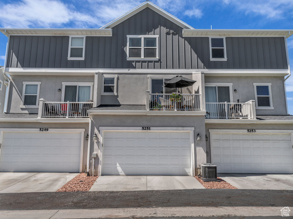 View of property featuring an attached garage, stucco siding, board and batten siding, and a balcony