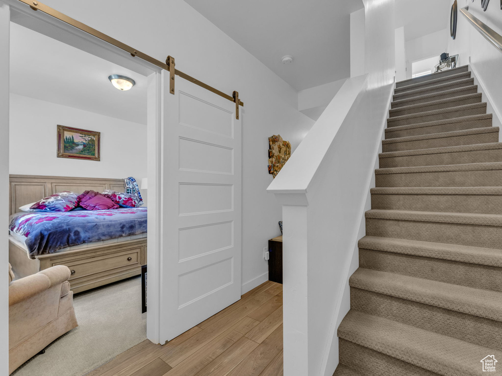 Staircase featuring wood finished floors and a barn door
