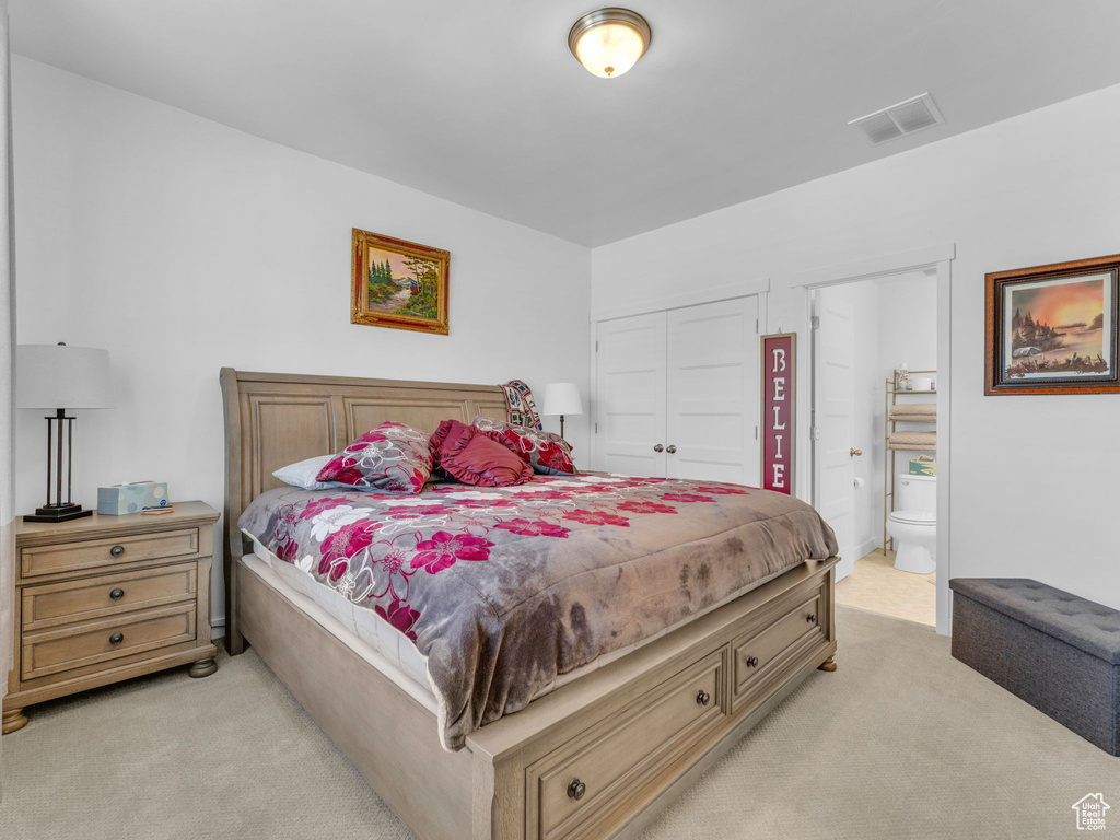 Bedroom featuring light colored carpet, a closet, and ensuite bathroom