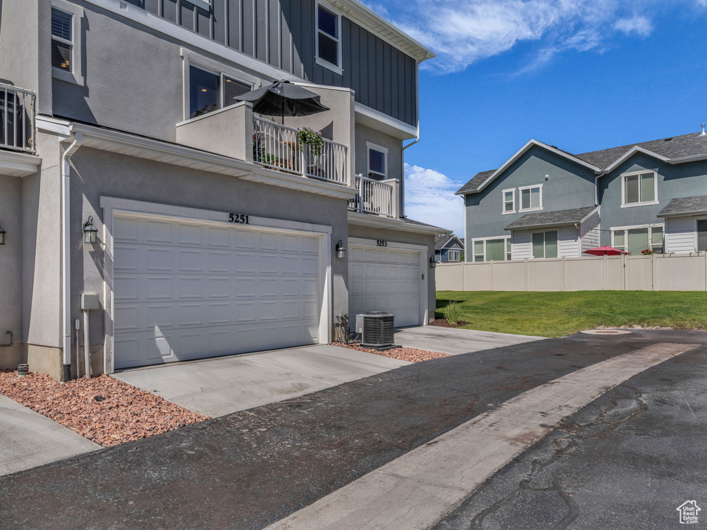 View of side of home with a garage, a balcony, stucco siding, board and batten siding, and concrete driveway
