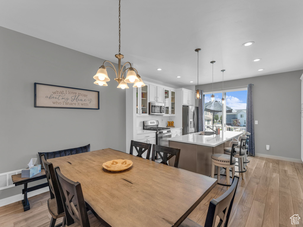 Dining room with light wood finished floors, recessed lighting, and a chandelier