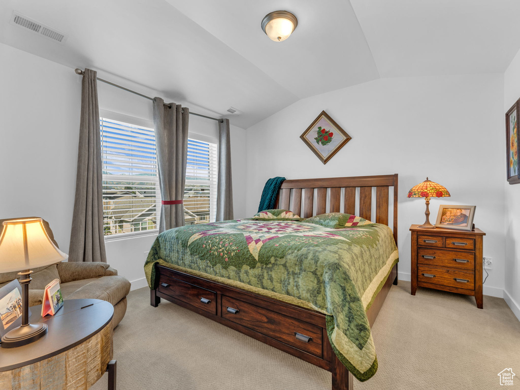Bedroom with light carpet and lofted ceiling