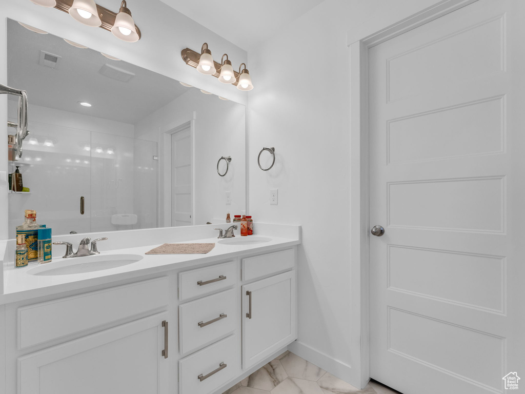 Bathroom featuring marble look tiles, double vanity, and a stall shower