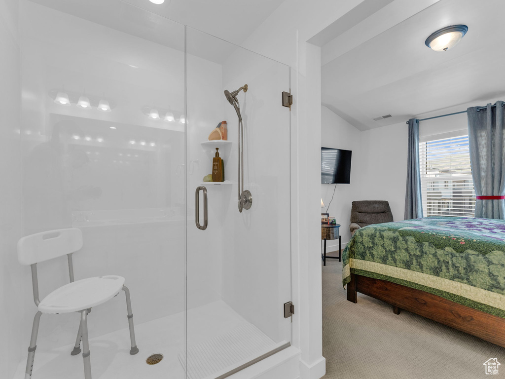 Full bath with ensuite bathroom, a stall shower, and lofted ceiling