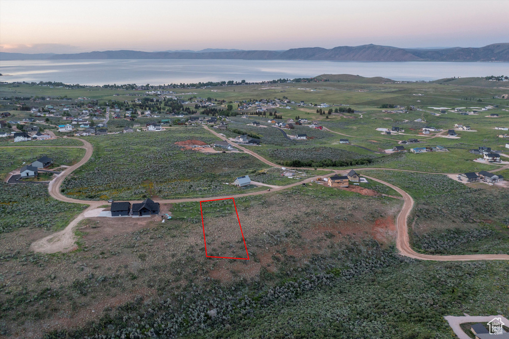 Aerial view at dusk of a water and mountain view and property boundaries highlighted