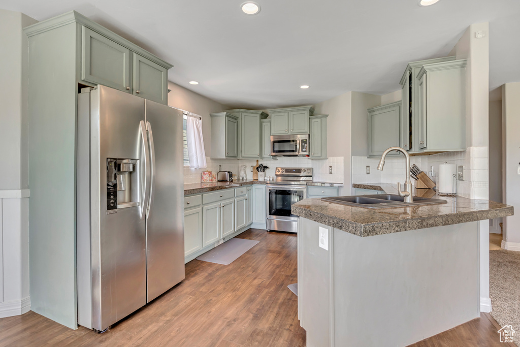 Kitchen featuring stainless steel appliances, a peninsula, green cabinetry, tile counters, and recessed lighting