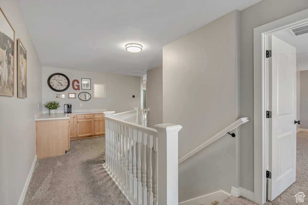 Corridor featuring light colored carpet and an upstairs landing