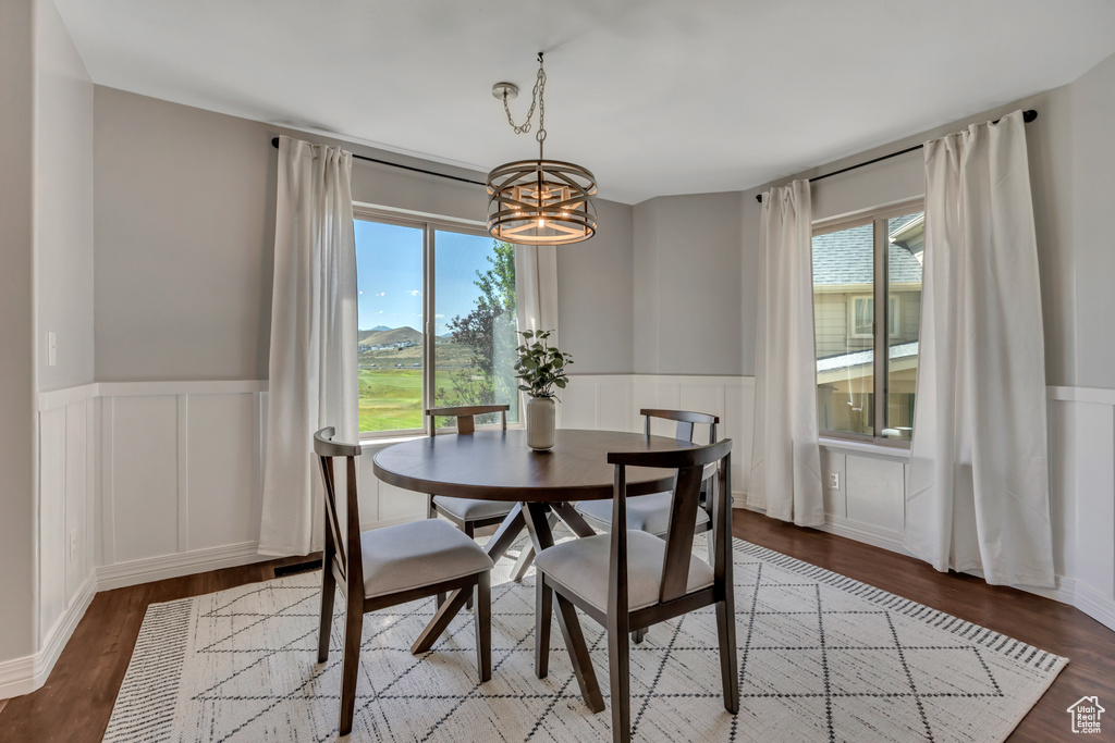 Dining area featuring a chandelier, a wainscoted wall, a decorative wall, and wood finished floors