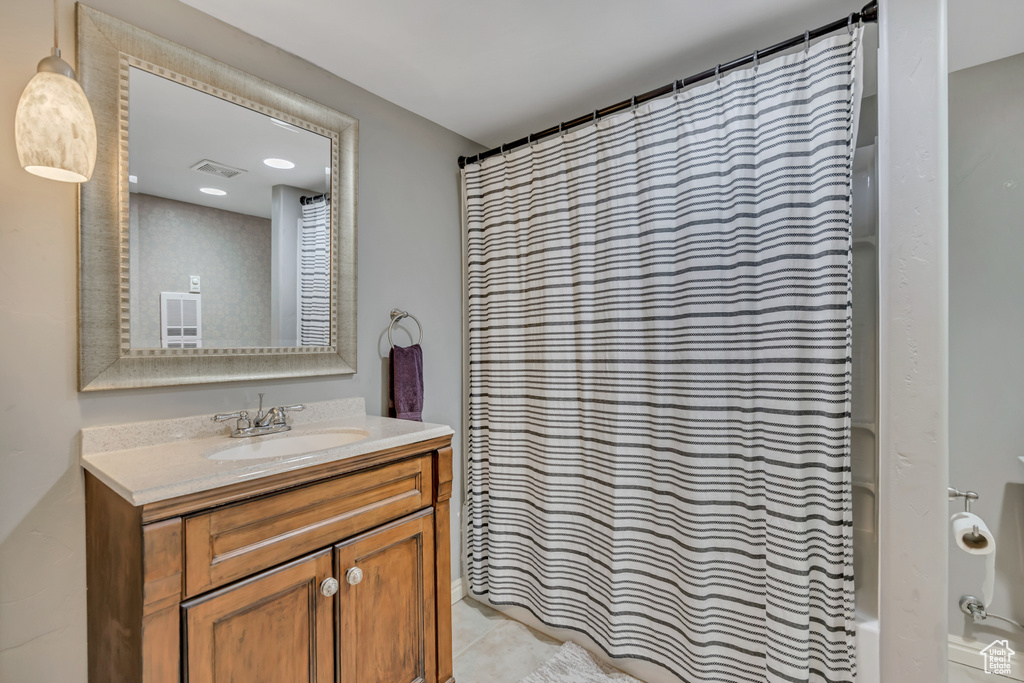 Full bath featuring vanity, shower / tub combo, and tile patterned flooring