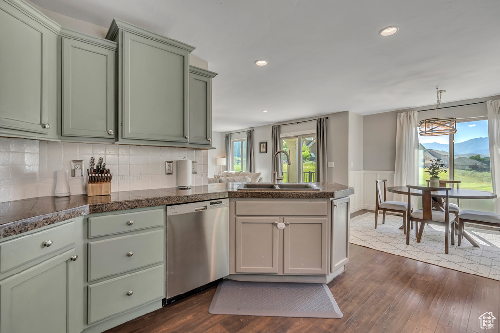 Kitchen with stainless steel dishwasher, green cabinetry, a peninsula, dark wood finished floors, and decorative backsplash