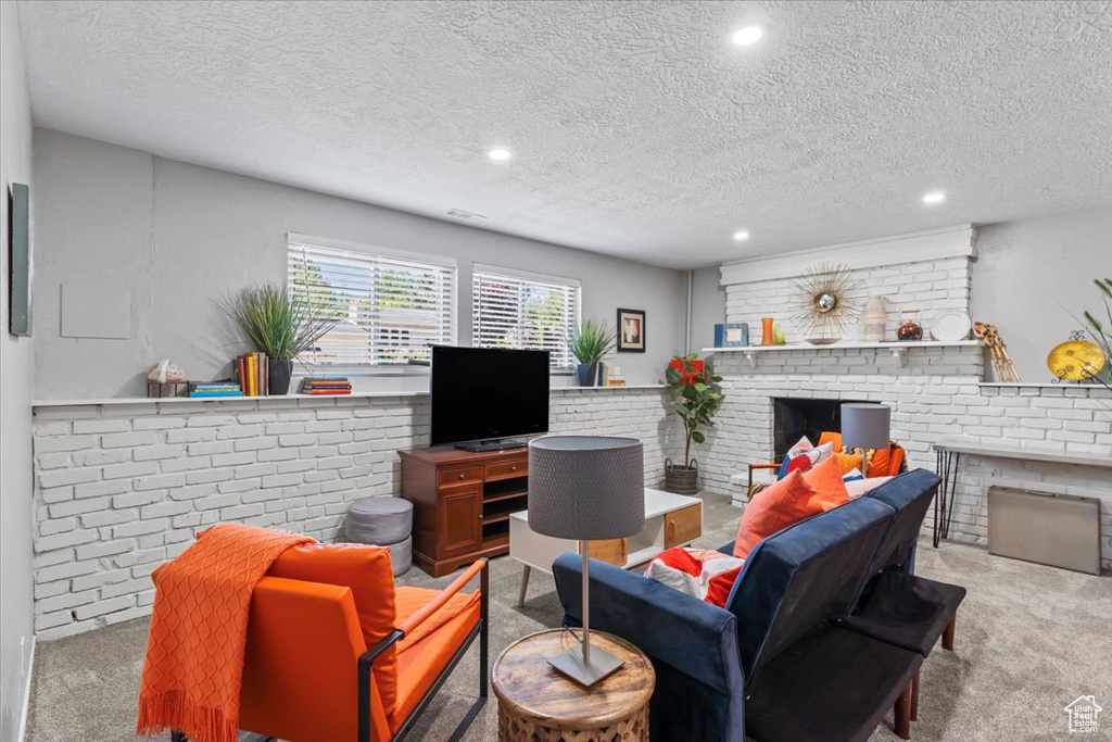 Carpeted living room with a brick fireplace, recessed lighting, and a textured ceiling