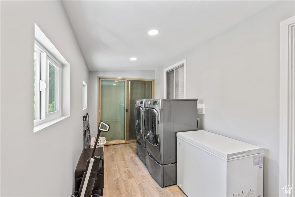 Laundry area with washer and dryer, light wood-type flooring, and recessed lighting