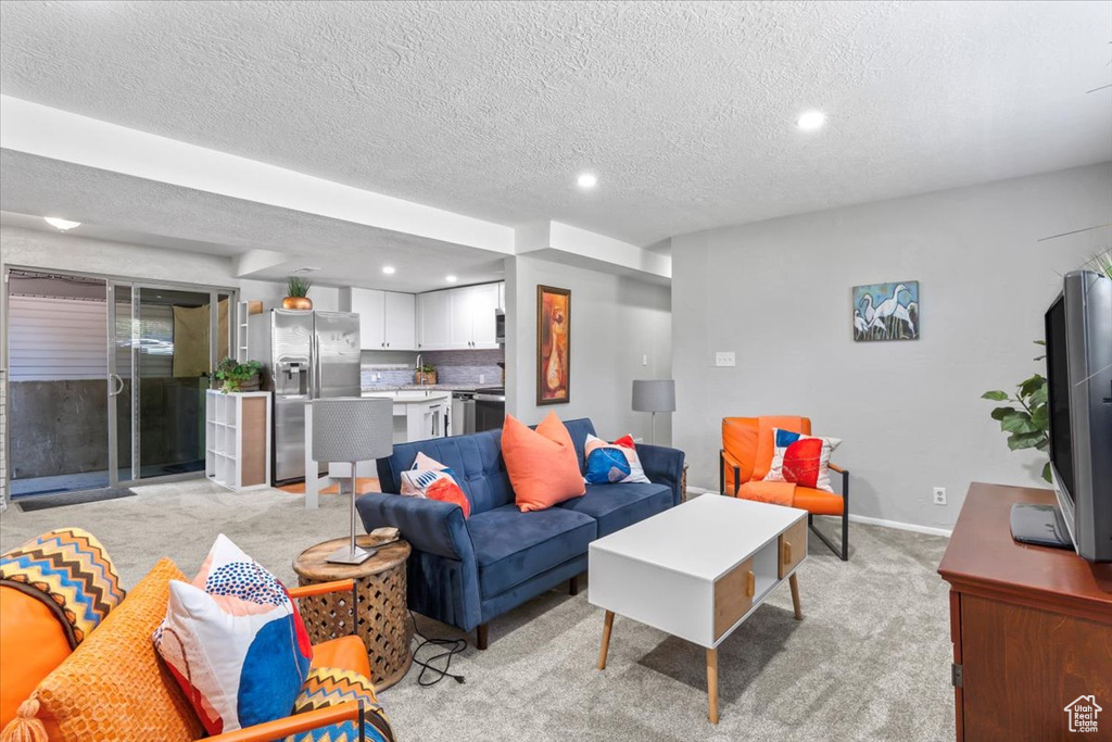 Living area with recessed lighting, light colored carpet, and a textured ceiling