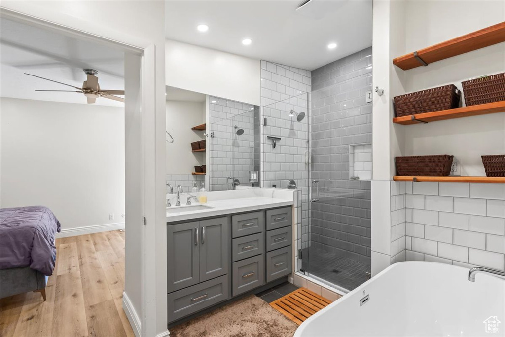 Bathroom with a stall shower, vanity, a soaking tub, ceiling fan, and wood finished floors