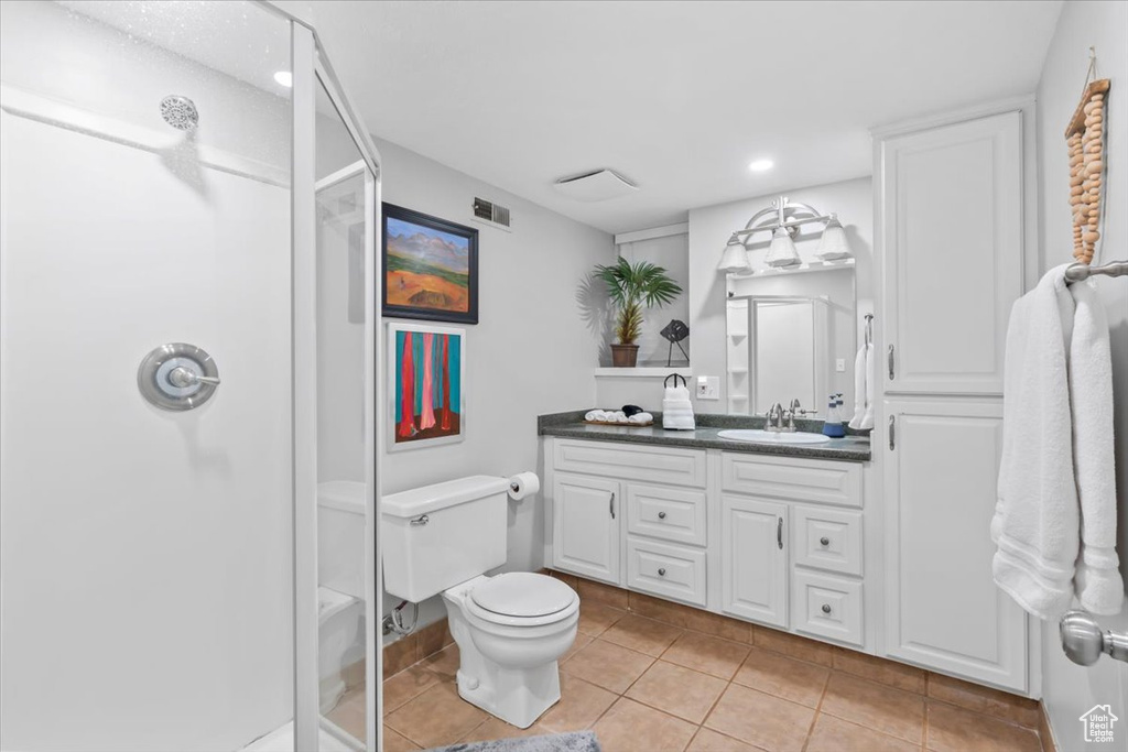 Bathroom featuring vanity, a shower stall, tile patterned floors, and recessed lighting