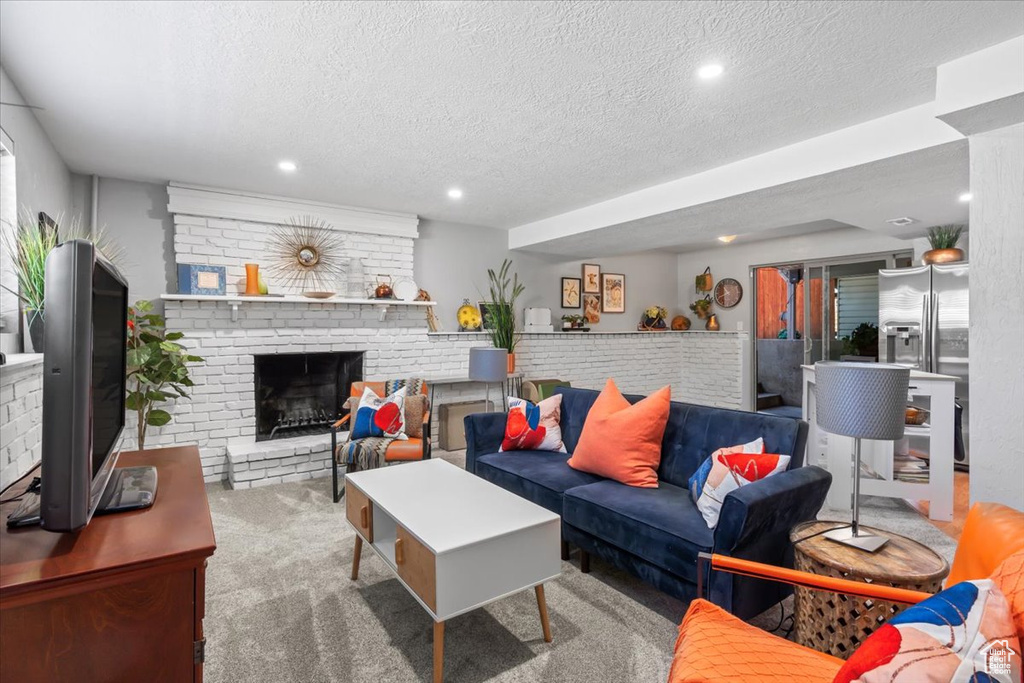Carpeted living area with a textured ceiling, recessed lighting, and a fireplace
