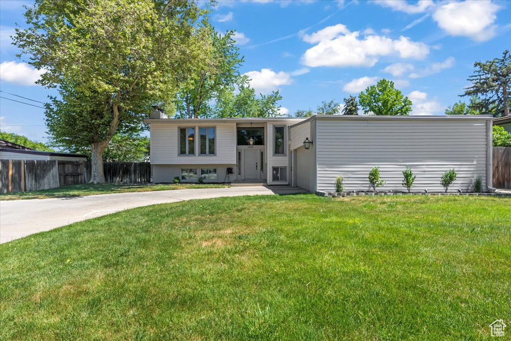Raised ranch featuring concrete driveway, a chimney, and a garage