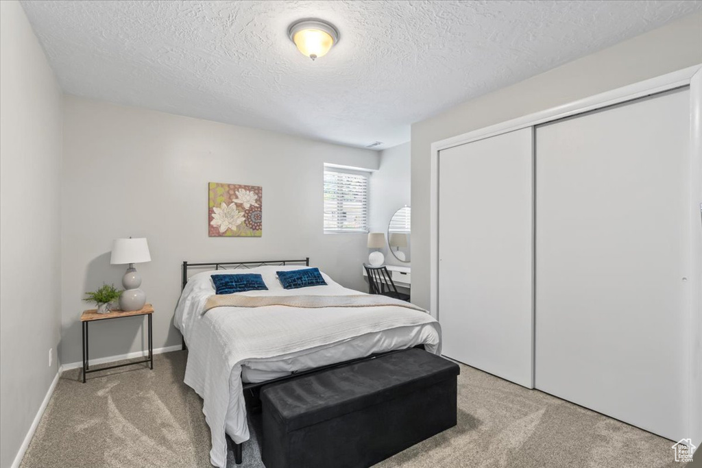 Bedroom with carpet, a textured ceiling, and a closet