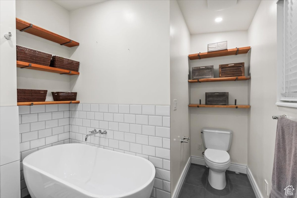 Bathroom with a soaking tub, tile patterned flooring, and tile walls