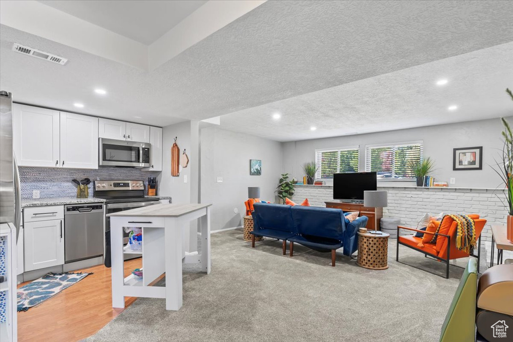 Kitchen with stainless steel appliances, white cabinets, recessed lighting, a textured ceiling, and tasteful backsplash