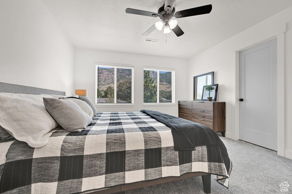 Bedroom with light carpet and a ceiling fan