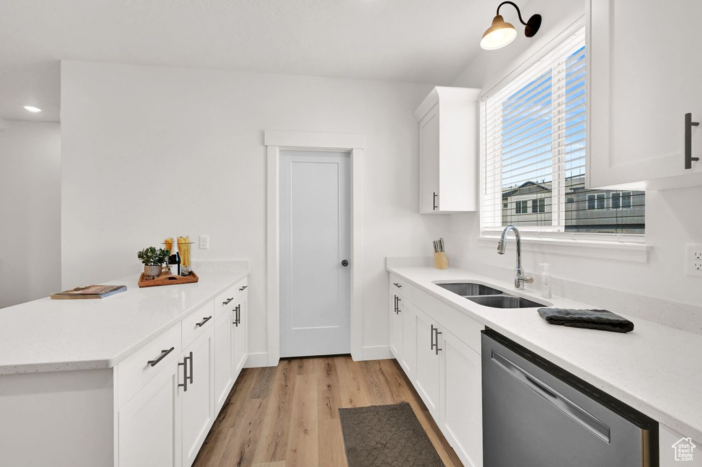 Kitchen featuring dishwasher, a peninsula, light wood finished floors, light countertops, and white cabinetry