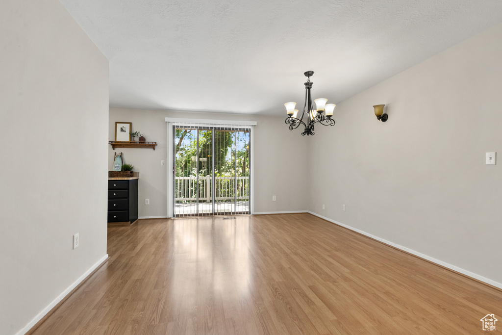Spare room with a chandelier and light wood-style flooring