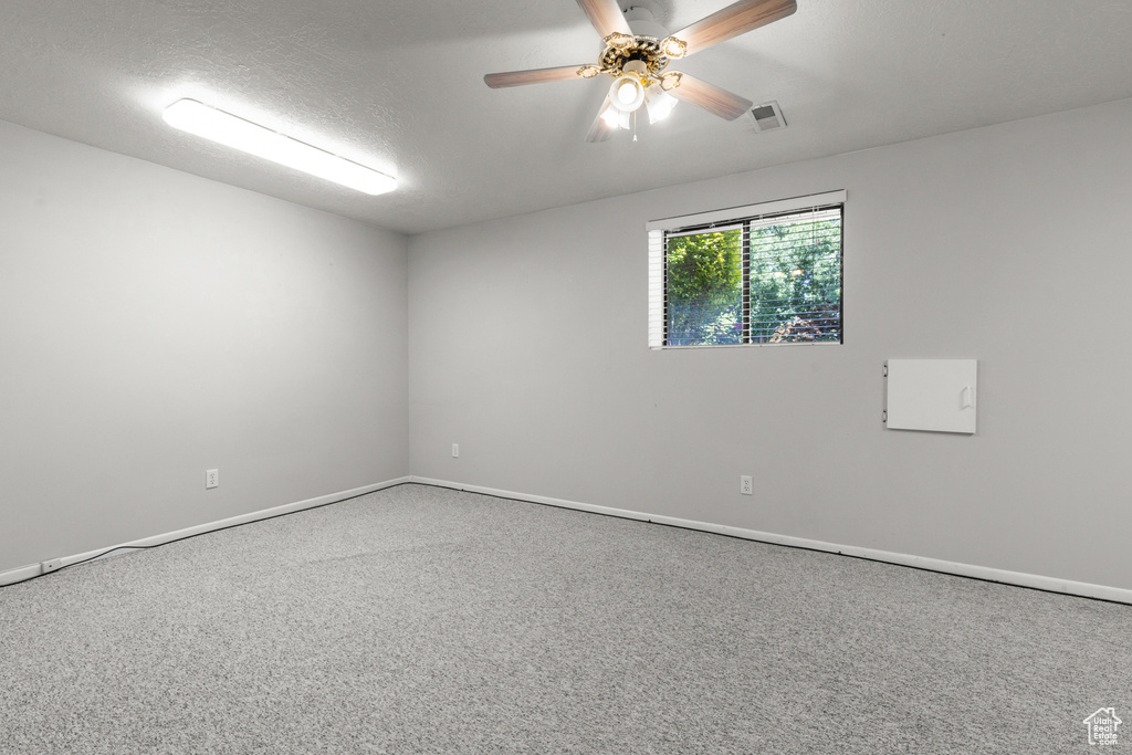Carpeted empty room with baseboards and a ceiling fan
