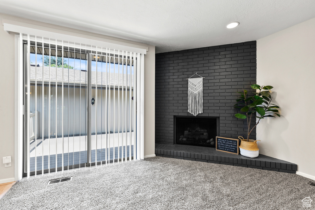 Carpeted living area featuring a fireplace and a textured ceiling