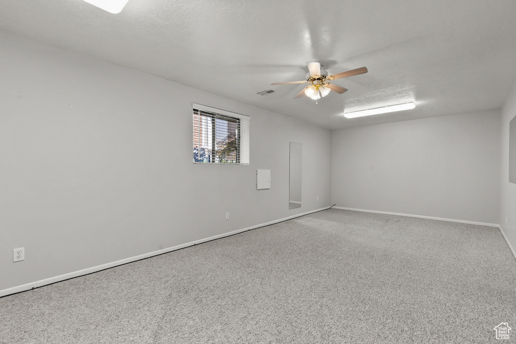 Spare room featuring a ceiling fan, a textured ceiling, and carpet