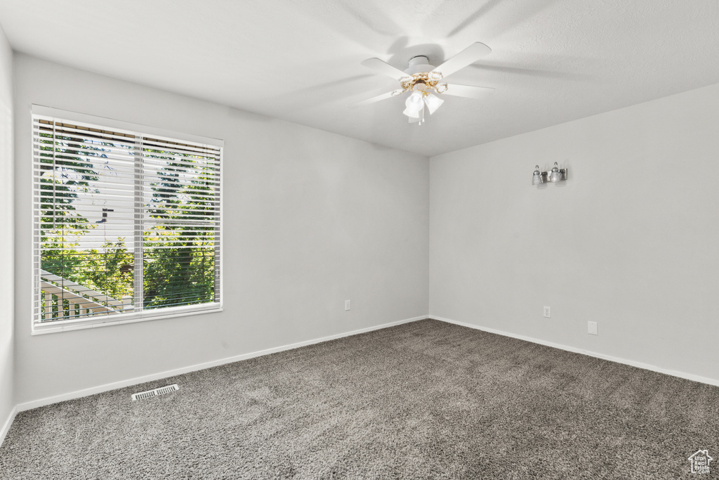 Carpeted empty room featuring ceiling fan and baseboards