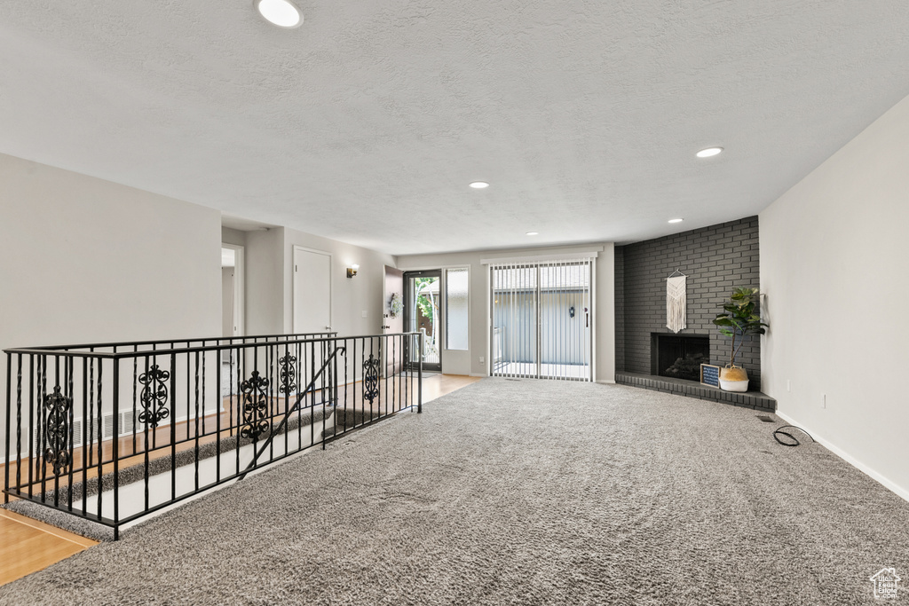 Carpeted spare room with a textured ceiling, a fireplace, and recessed lighting