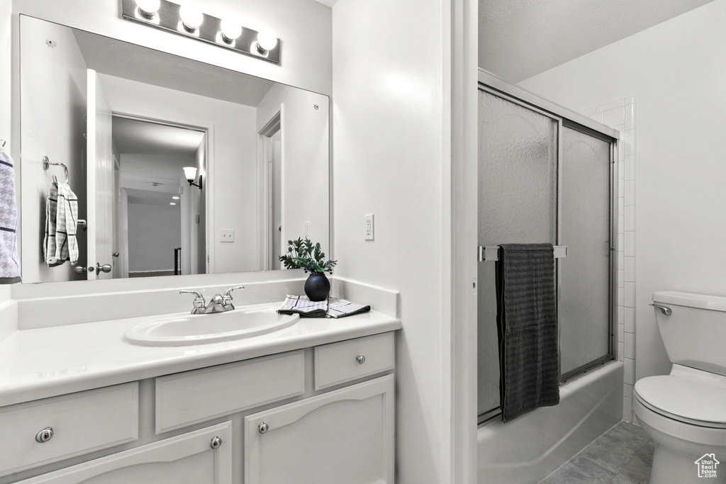 Bathroom featuring vanity and bath / shower combo with glass door