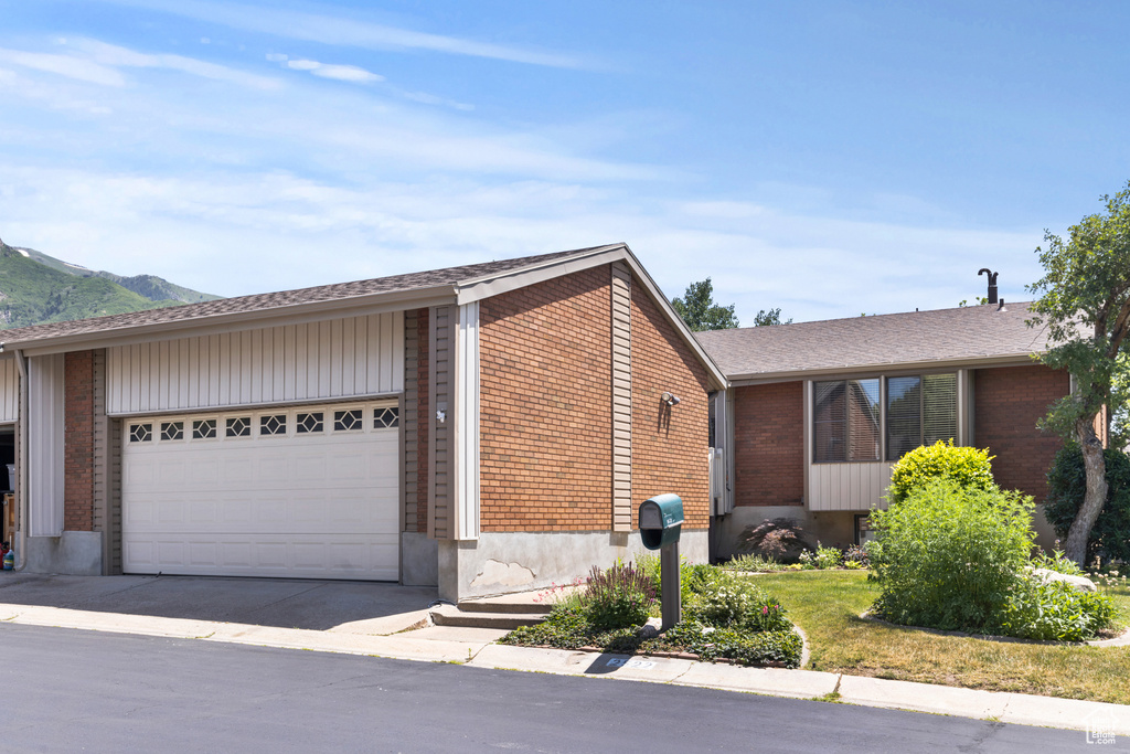 View of front of house featuring a garage, brick siding, driveway, and a mountain view