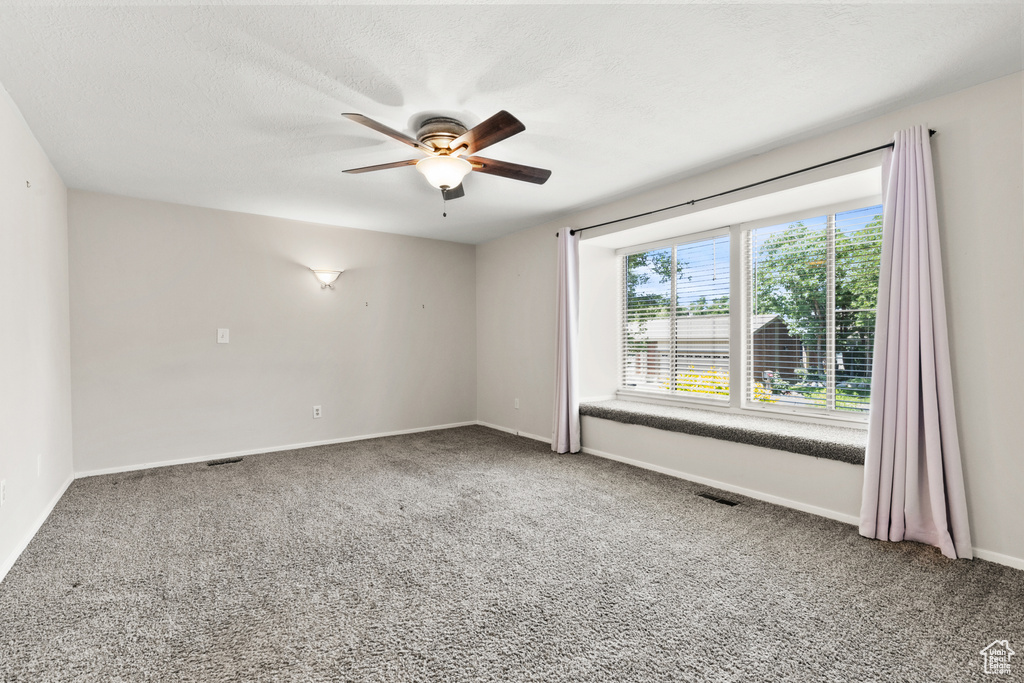 Carpeted spare room featuring ceiling fan and baseboards