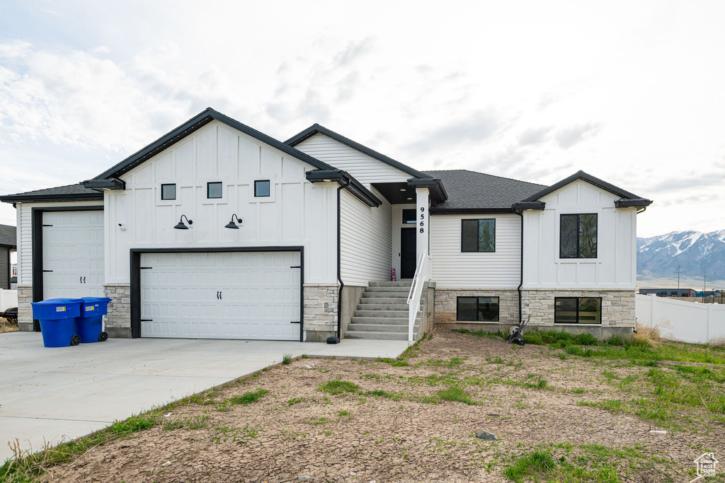 Modern farmhouse style home featuring board and batten siding, driveway, and stone siding