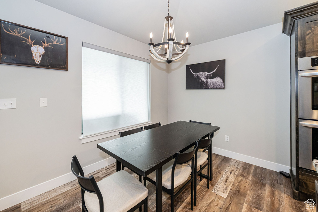 Dining room with a chandelier and dark wood-style floors