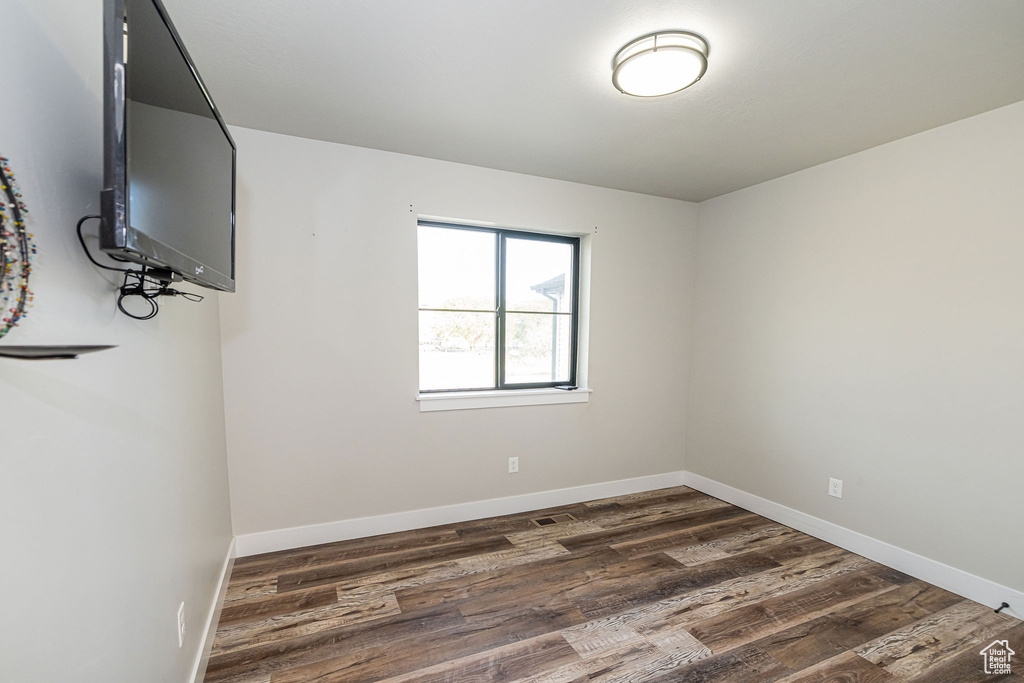 Empty room with dark wood-style floors and baseboards
